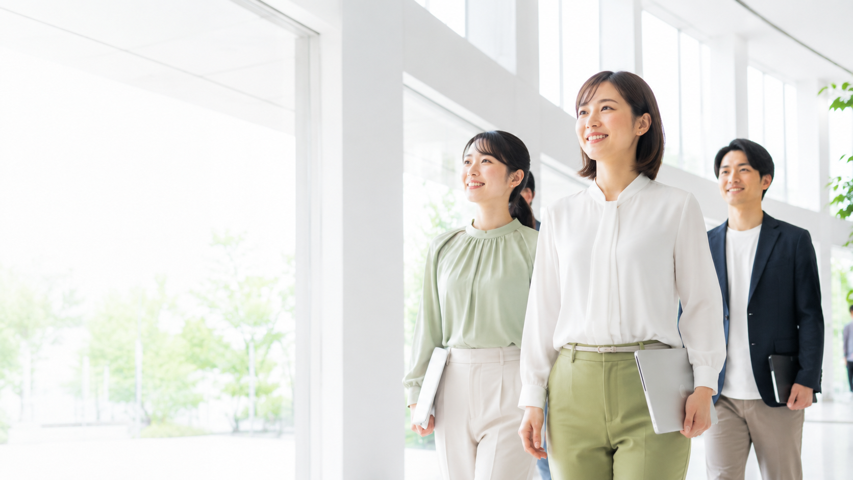 明るいオフィスを歩く3人の社員